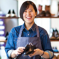 person smiling at camera while polishing shoe